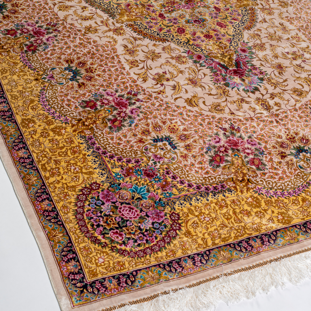 Handwoven silk rug in cream, gold, and blush tones featuring floral medallion, delicate vines, and ornate pastel detailing throughout.

